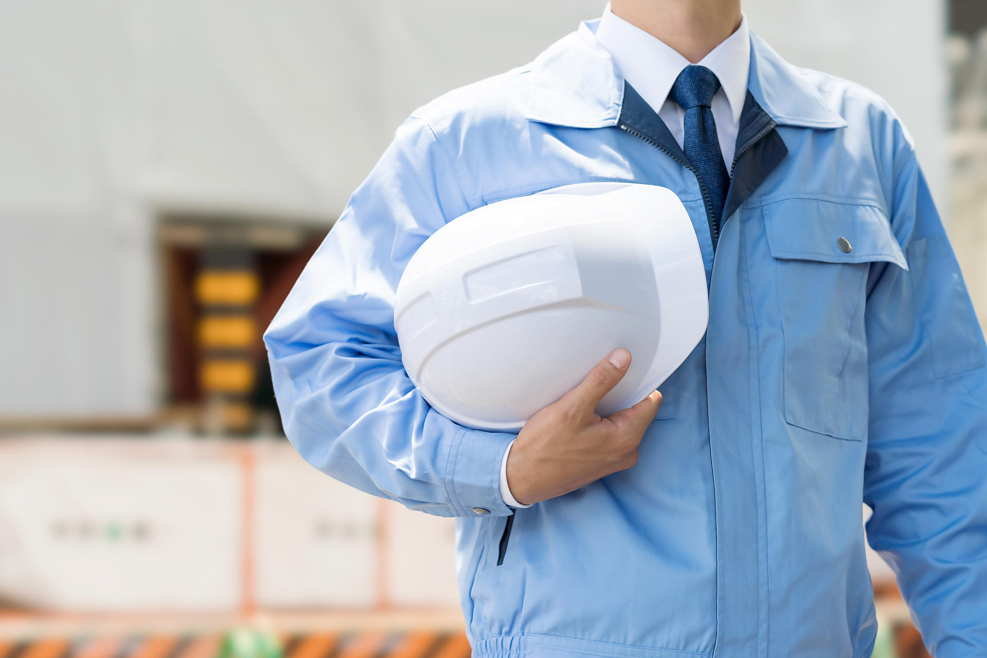 ヘルメットを持っている作業服の人の画像