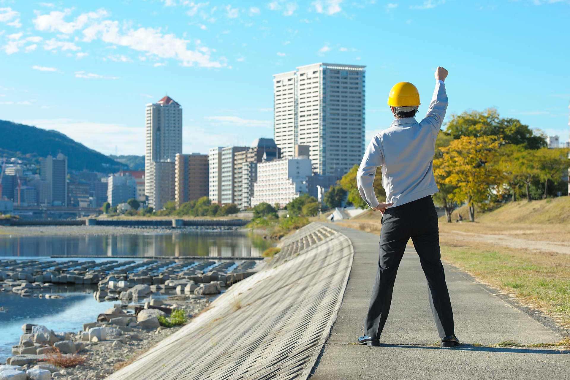 片手を上げる作業服の男性の画像